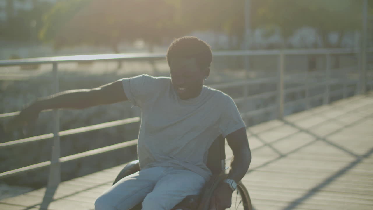 joven negro en silla de ruedas cantando y bailando en el parque de la ciudad