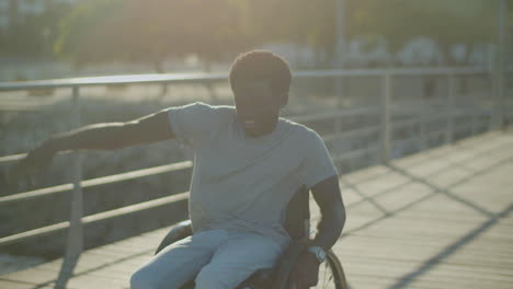 joven negro en silla de ruedas cantando y bailando en el parque de la ciudad