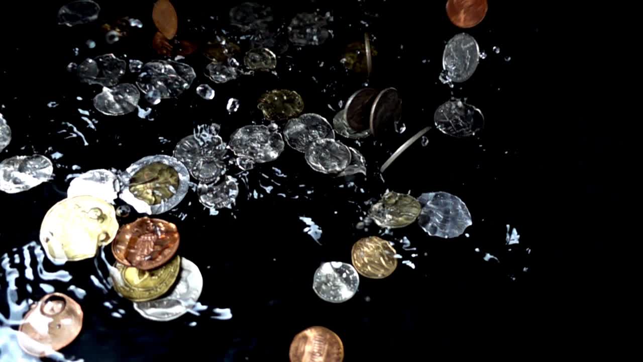 Monete che cadono nell'acqua. Rallentatore