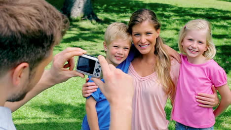 a man takes a photo of his family who are embracing before they turn to the camera and smile