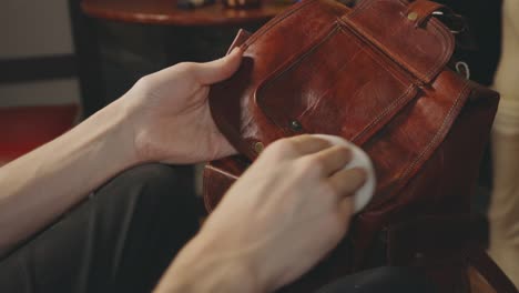 person polish a flap retro leather bag to make it shiny