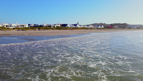 Niedrige-Luftaufnahme-über-Sanfte-Wellen,-Die-Am-Sandstrand-In-Paternoster-Brechen