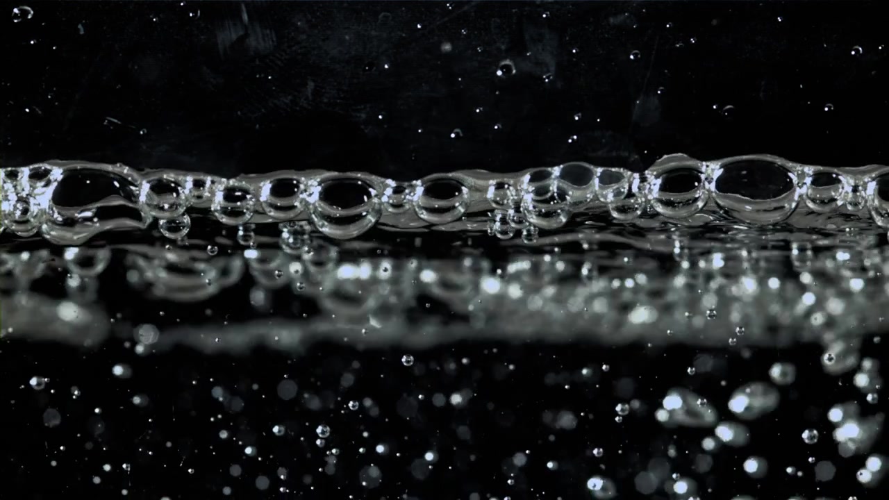 Gros plan de bulles d'eau se formant et se déplaçant sur un fond noir