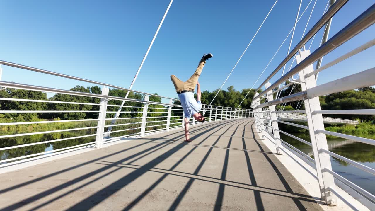 Man performs one arm handstand on bridge