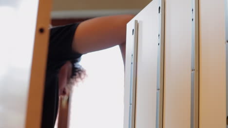 Teenager-With-Curly-Hair-Assembling-A-Shelf