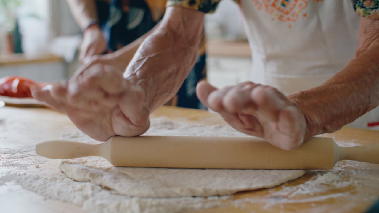 Nonna che stende l'impasto su un tavolo infarinato durante un momento di cucina in famiglia