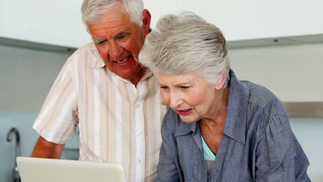 una pareja de mayores usando la computadora portátil en el mostrador