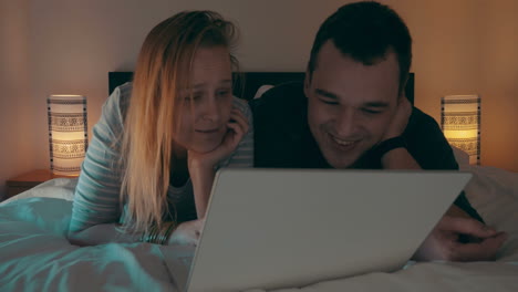 couple in bed watching movie on laptop