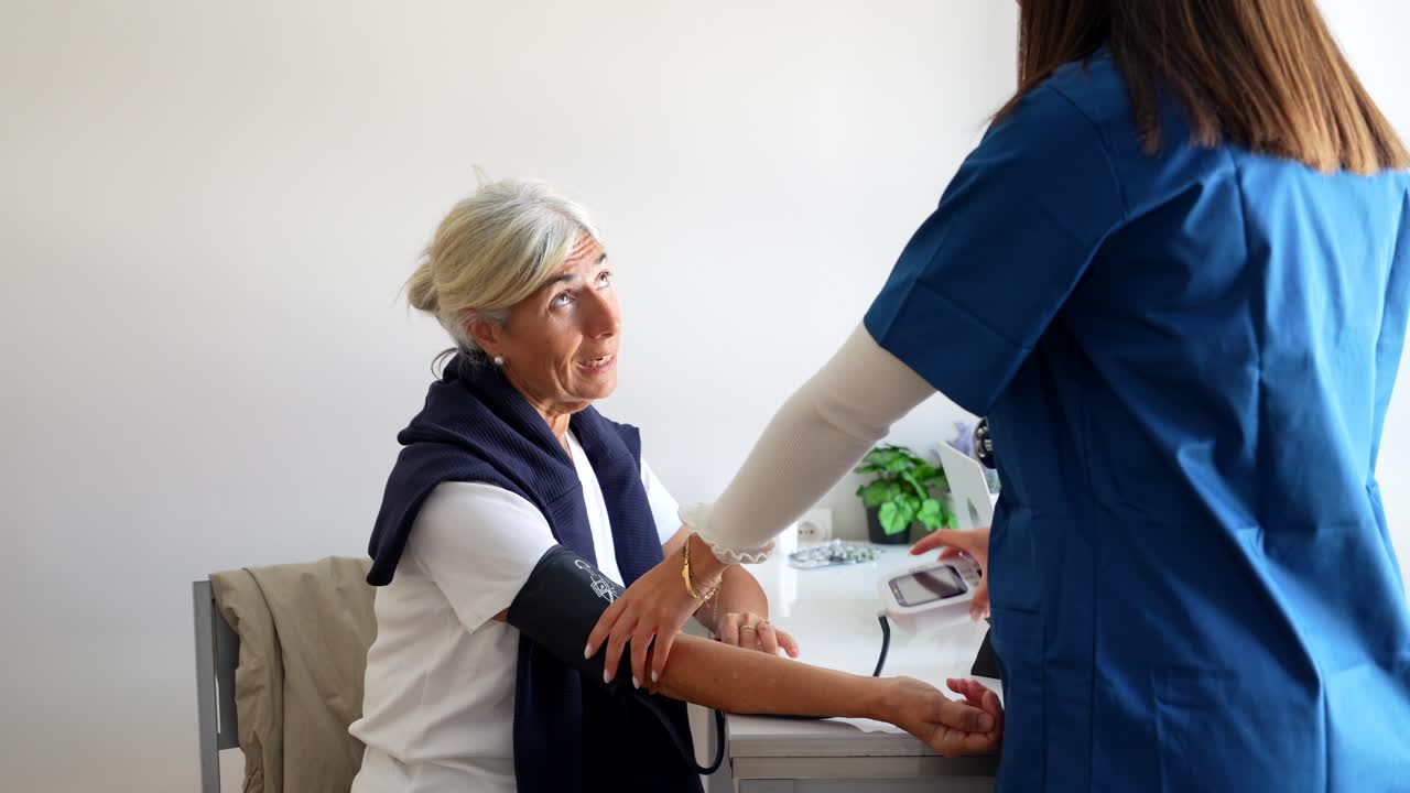 Nurse checking blood pressure of elderly patient