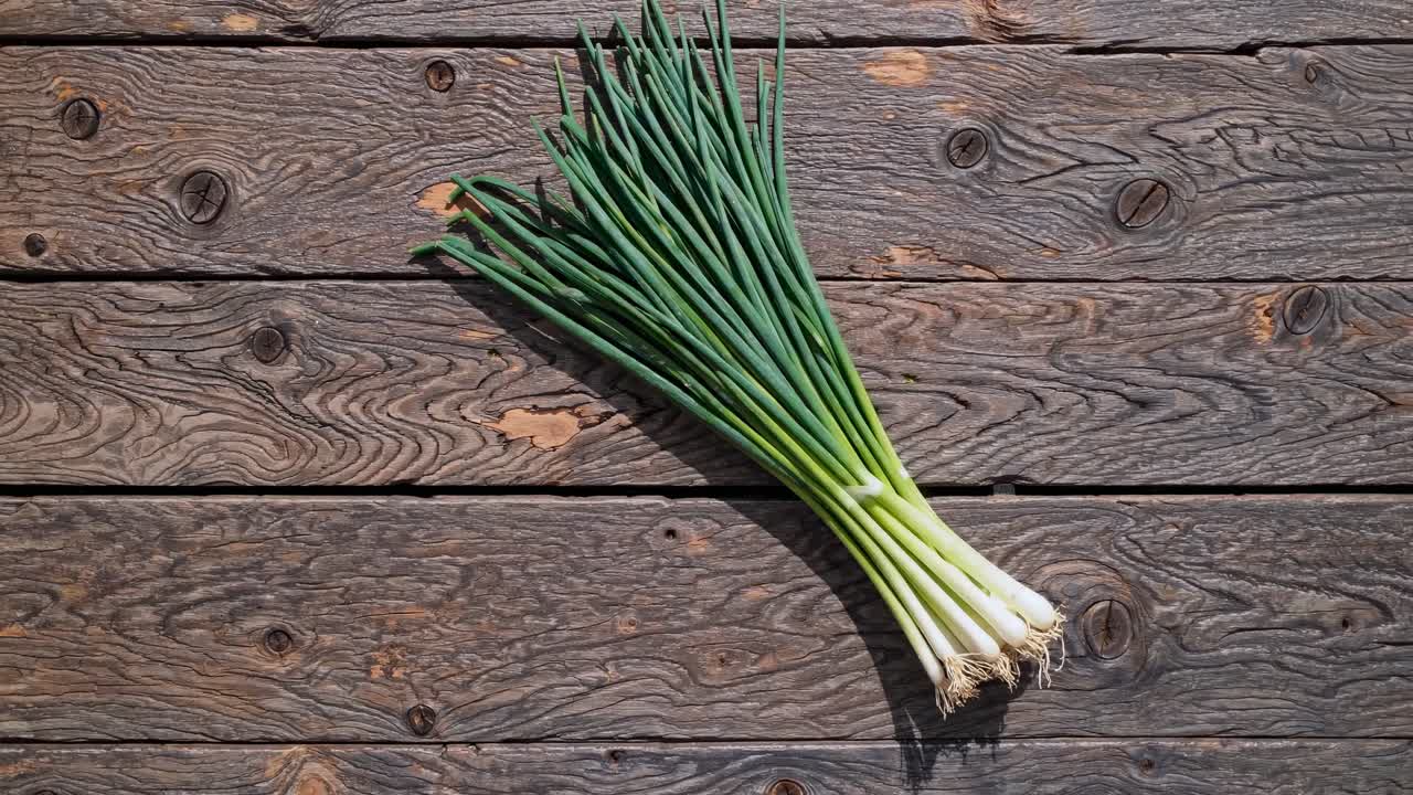 Top-down view of fresh green onions on rustic wooden planks