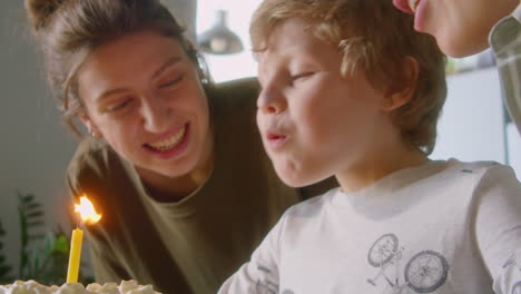 Happy Child Blowing Candle on Birthday Cake at Family Celebration