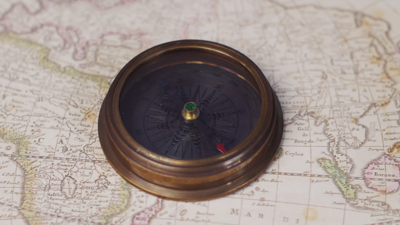 A nautical compass lying on a vintage map of the world