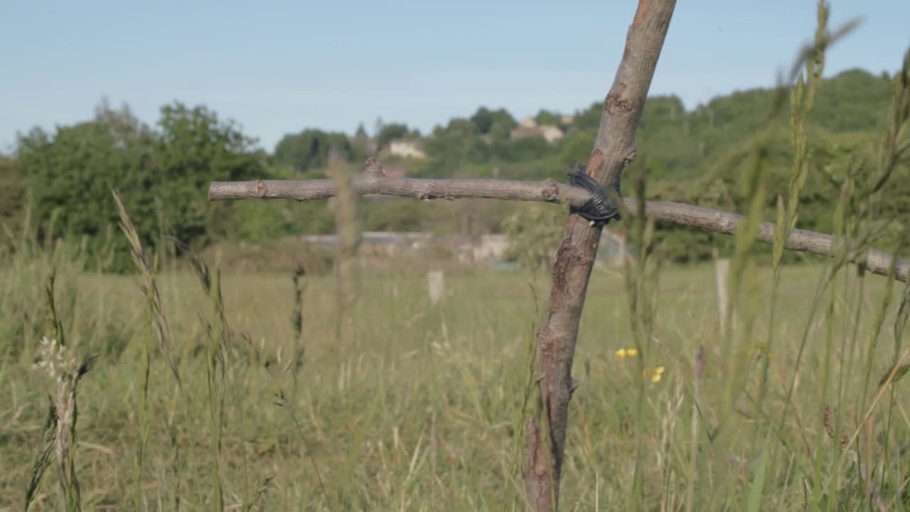 Handmade wooden cross in a field wide panning shot