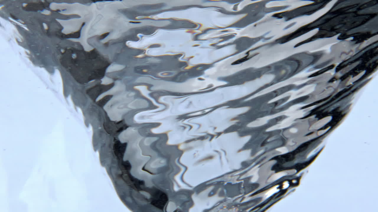 Cold gin making funnel inside container closeup. Tonic water column in glass