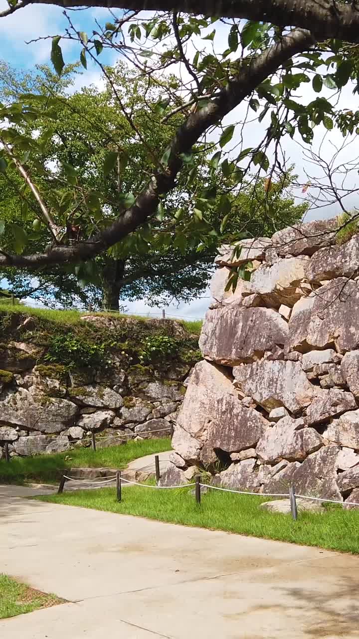 Panning vertical at ancient Japanese Takeda Castle Ruins, historic temple, greenery, blue sky landscape