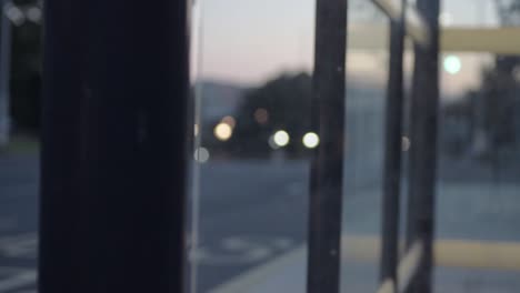 urban city defocused vehicle ights at dusk through bus stop windows