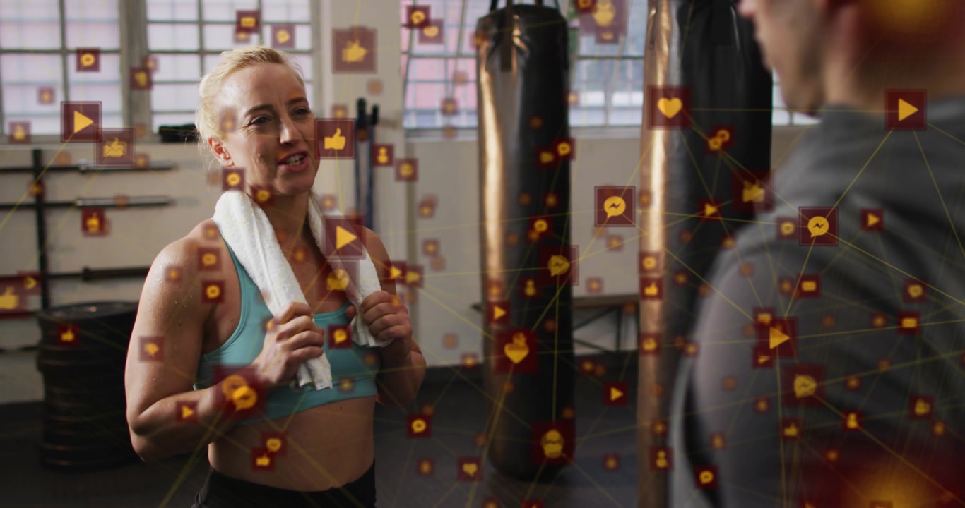 Fitness client catching breath using towel and speaking to trainer beside bag, icons showing growth