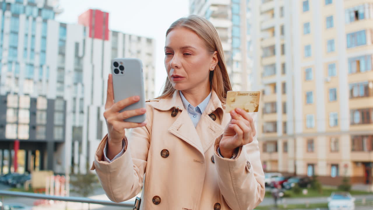 Caucasian businesswoman using credit card and smartphone shopping online on downtown city street