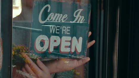 Woman-opening-shop-turning-over-signboard