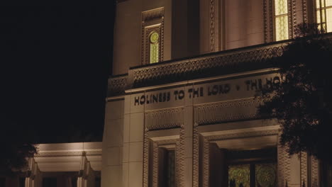 inscription above lds church mormon temple front doors that says "holiness to the lord, the house of the lord" at night in gilbert, arizona