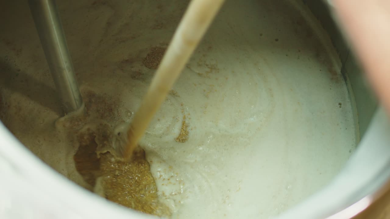 Craft beer production factory, brewery manufacture. Putting barley malt grains in conveyor close-up. Brewing, cooking alcohol in metal vats bottles