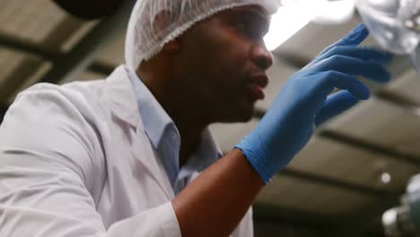 Attentive-worker-examining-a-bottle