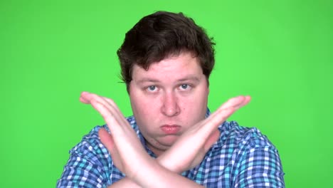 portrait of young man showing stop sign, dislike, rejecting gesture, disagree sign, crossing hands