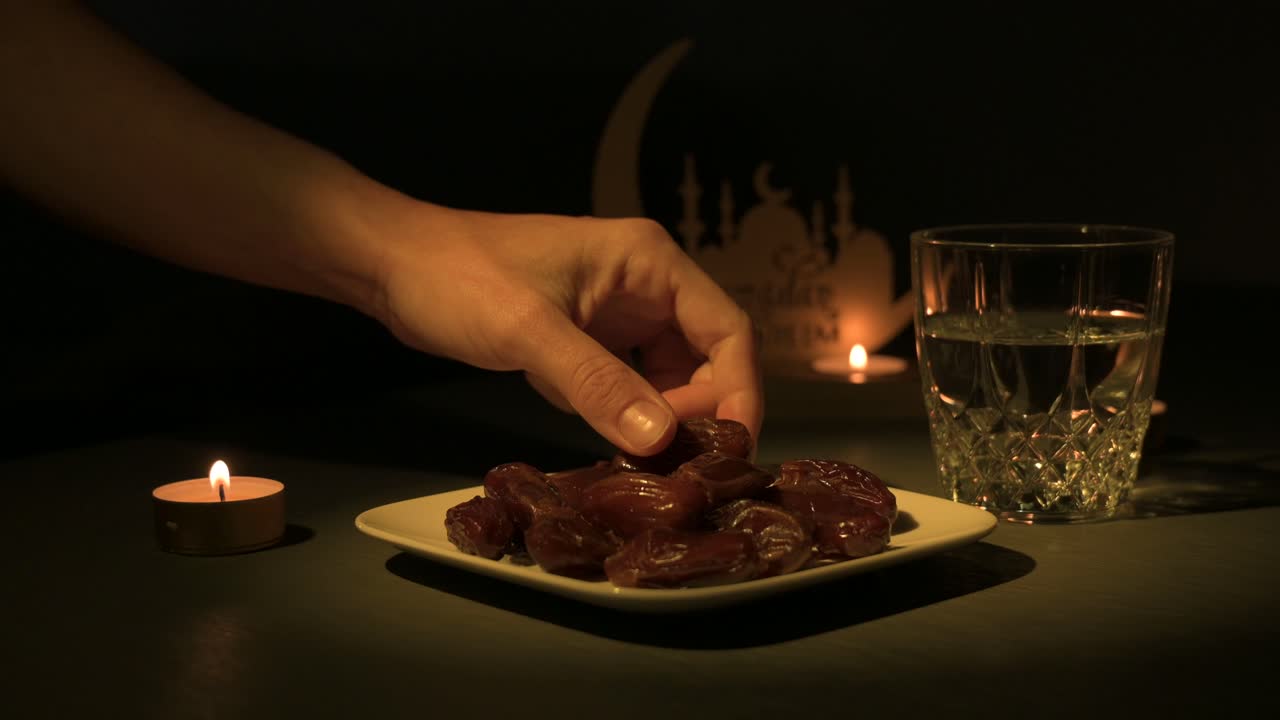 Hand picking a date from plate to break fast during Ramadan by candlelight