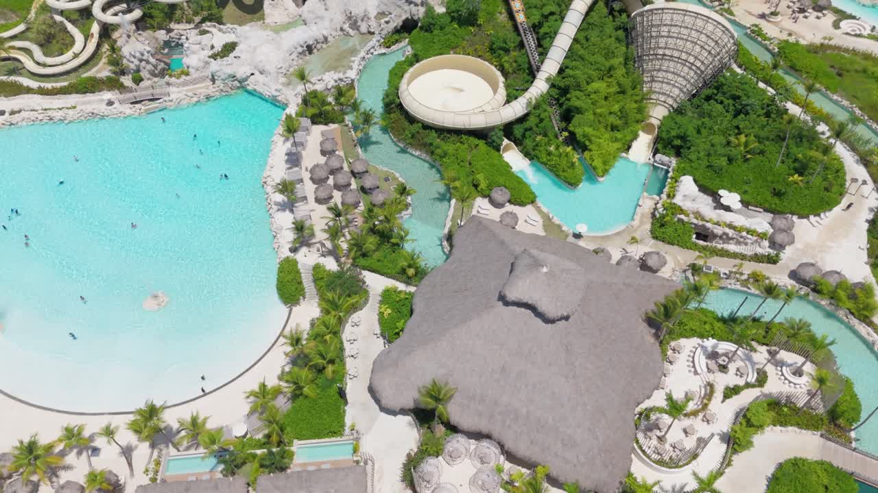 People enjoying leisure time in aqua park, swimming, sliding down water slide aerial orbit