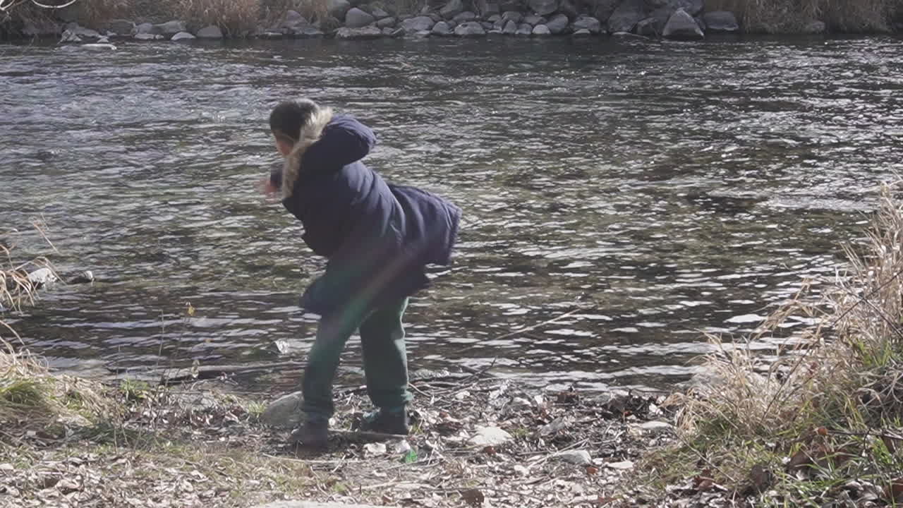 겨울에 강에 막대기를 던지는 아이