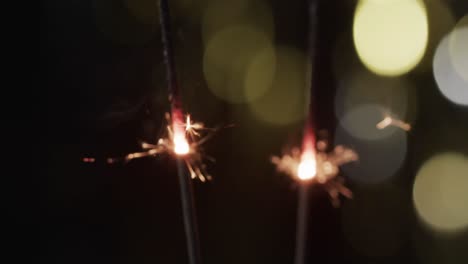 video of close up of sparklers with bokeh and copy space on black background