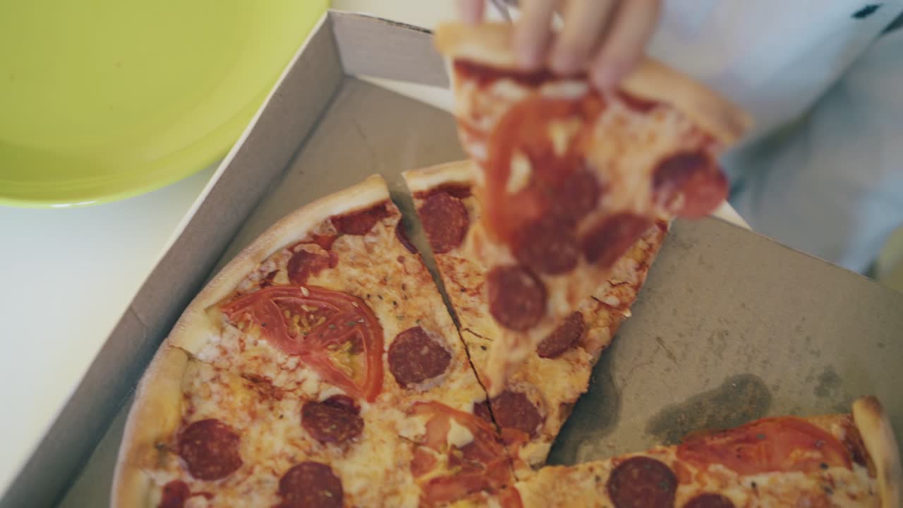 ребёнок берёт кусок свежей пиццы и ставит на тарелку крупный план.