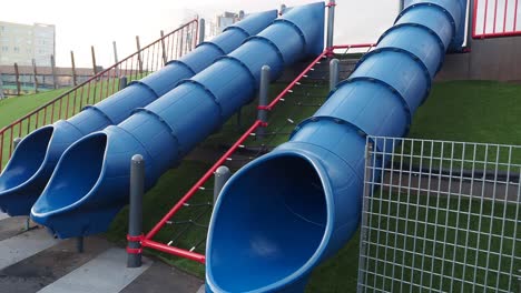 tres diapositivas azules en un patio de recreo