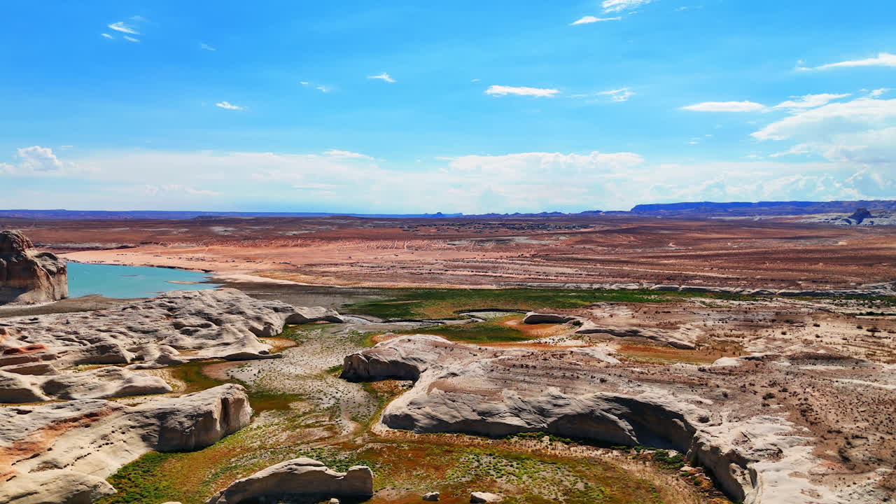 Terbang di atas lanskap berbatu di hari yang cerah. Mendekati perairan biru di tanah Utah, AS, yang sepi dekat tengaran terkenal Lone Rock