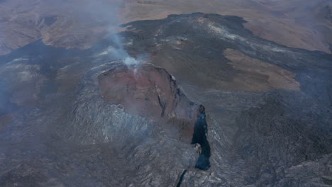 Iceland-Fagradalsfjall-volcano-flying-above-volcanic-fissure-cone,-black-lava-landscape,-circle-pan,-day