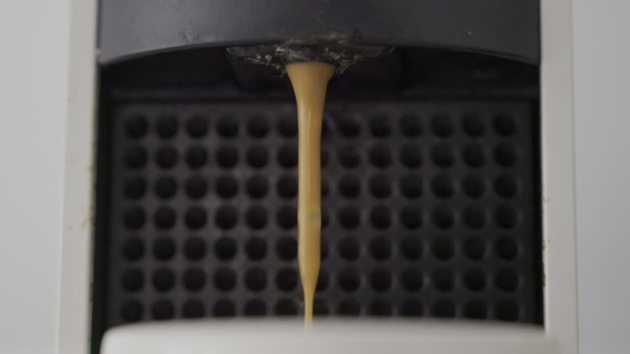 Close up of coffee pouring into a white cup from a machine