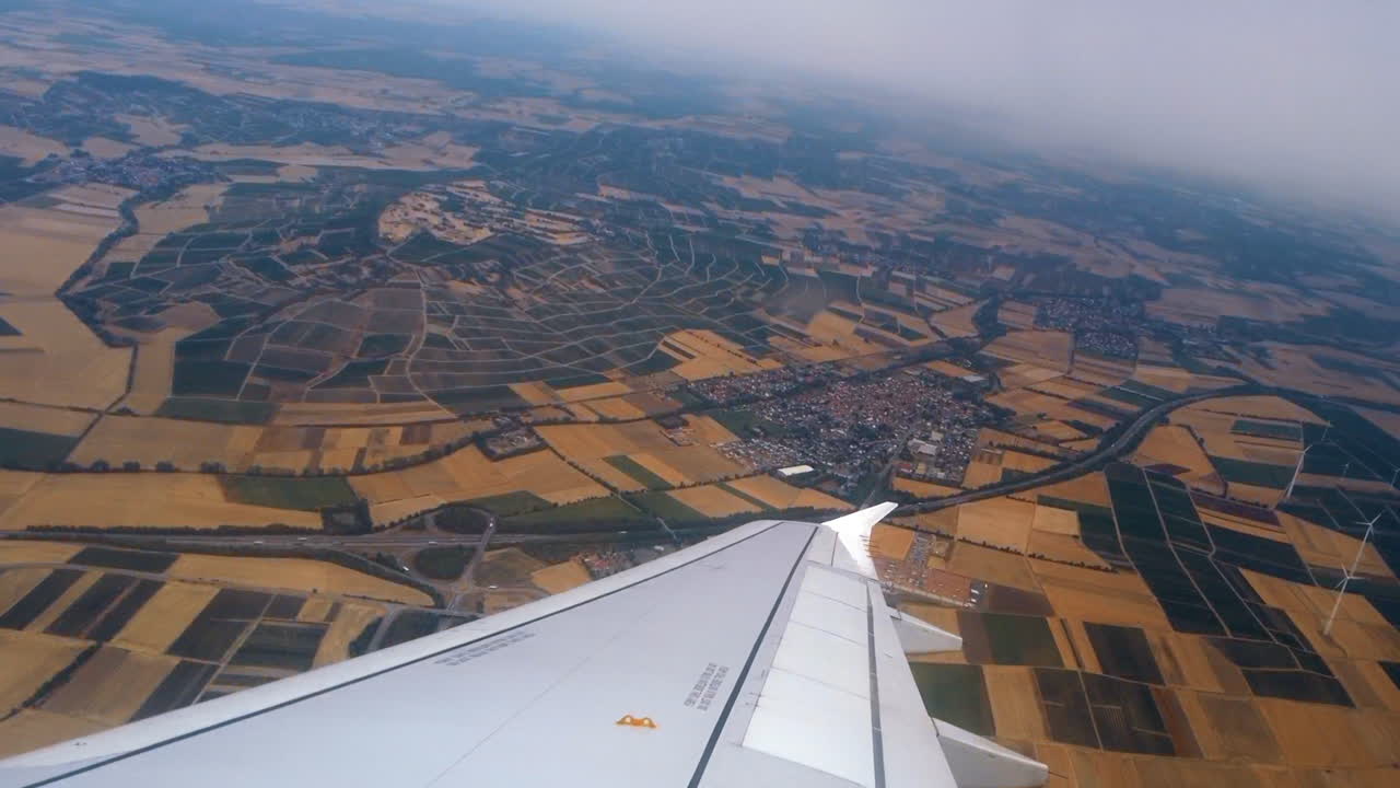 Udsigt fra et flyvindue over flyets vinge med land i baggrunden