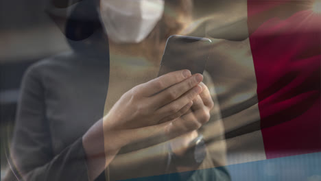 french flag waving against woman wearing face mask using smartphone