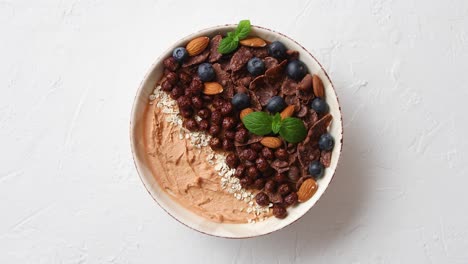 chocolate and blueberry smoothie or yogurt  with cocoa cornflakes  granola  mint leaves and almonds