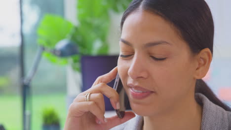 Cerca-De-Una-Mujer-De-Negocios-Que-Trabaja-En-La-Oficina-Sentada-En-Un-Escritorio-Hablando-Por-Teléfono-Móvil