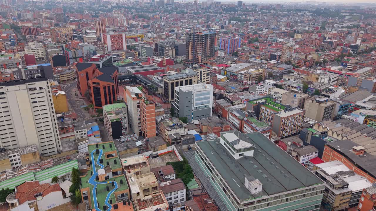 Aerial shot rising over Bogotá as a rooftop worker appears among dense urban buildings