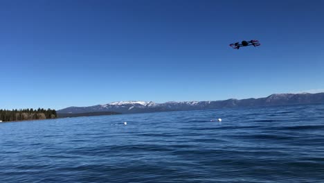 drone moviéndose hacia arriba y hacia abajo en el aire con cielo azul en el fondo y lago de agua debajo
