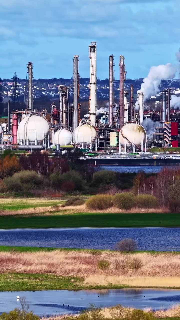 Industrial oil refinery releasing smoke into blue sky, aerial view