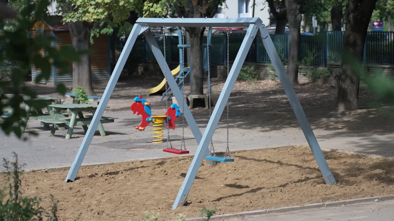 Empty playground with swings and spring rocker in a sunny park
