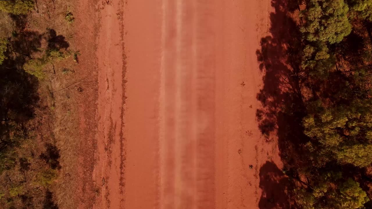 vista aérea de una polvorienta carretera de tierra recta con tráfico de vehículos en el remoto interior de australia
