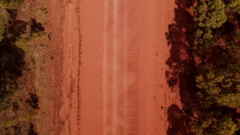 aerial overhead view of dusty straight dirt road with vehicle traffic in remote outback australia