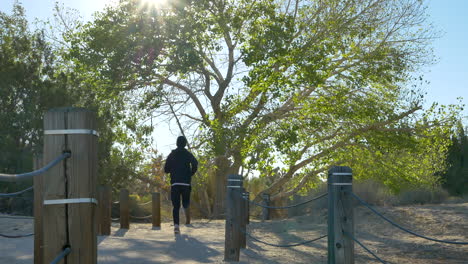 a young fit white man on a cold fall morning jog after a workout running away from the camera through a peaceful desert nature preserve