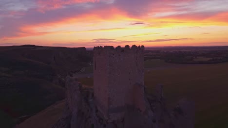 drone shot of the medieval oreja castle perched on a hilltop at golden hour near aranjuez, spain. scenic sunset over rural fields and rocky landscape.