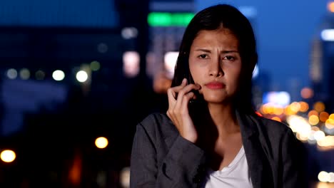 Asian woman using smartphone for work at city. Woman using smartphone with angry emotion.