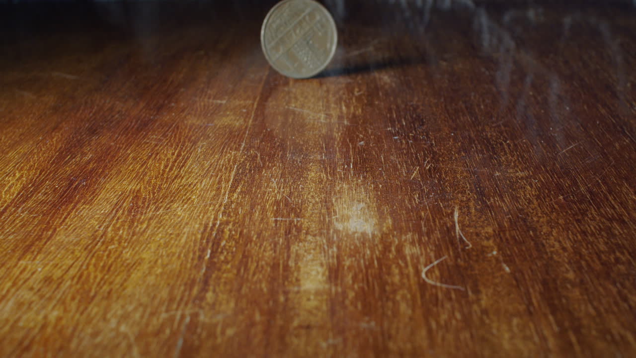 primer plano de una moneda de 10 francos volteada sobre una mesa de madera, estática, lenta